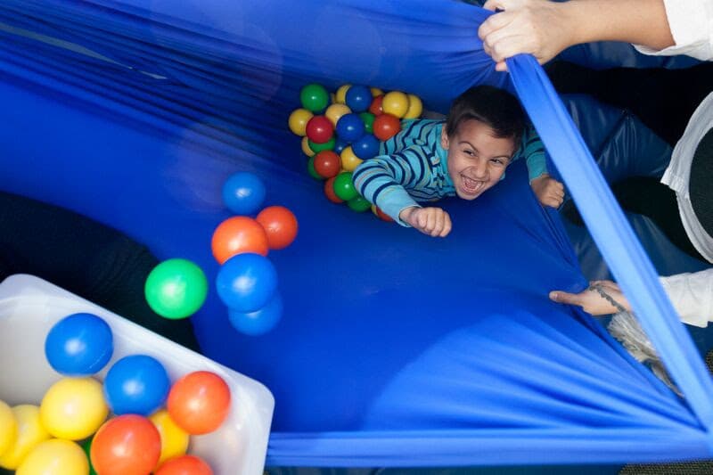 Child in sensory gym with colorful balls during therapy session